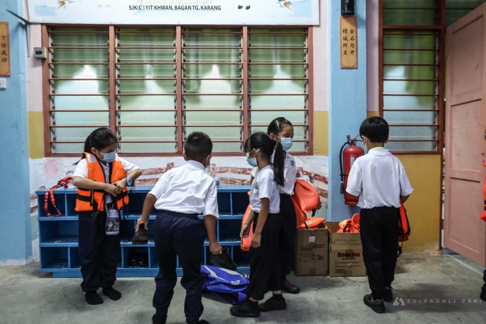 Murid SJK (C) Yit Khwan meletakkan jaket keselamatan sebelum masuk ke kelas sewaktu tinjauan di Kampung Bagan, Tanjung Karang, Selangor pada hari ini. Media Selangor/Zulfadhli Zaki